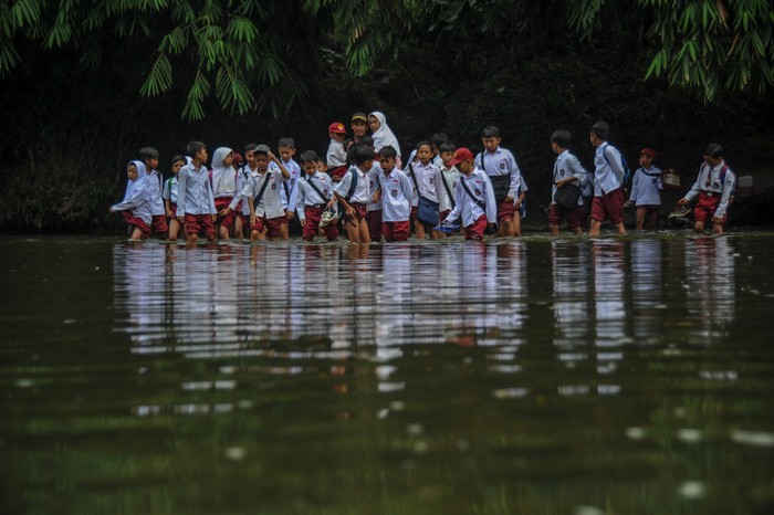 SISWA SEBERANGI SUNGAI UNTUK SEKOLAH Warga menggendong anaknya untuk menyeberangi Sungai Ciujung di Desa Sukaluyu, Cikadu, Cianjur Selatan, Kabupaten Cianjur, Jawa Barat, Rabu (10/8/2022). Sejak tahun 2018, ratusan siswa dari Desa Karyabakti terpaksa harus menerjang Sungai Ciujung untuk sekolah di SDN Padawaras Desa Sukaluyu karena tidak ada akses jalan lain untuk menuju sekolah mereka. ANTARA FOTO/Raisan Al Farisi/YU