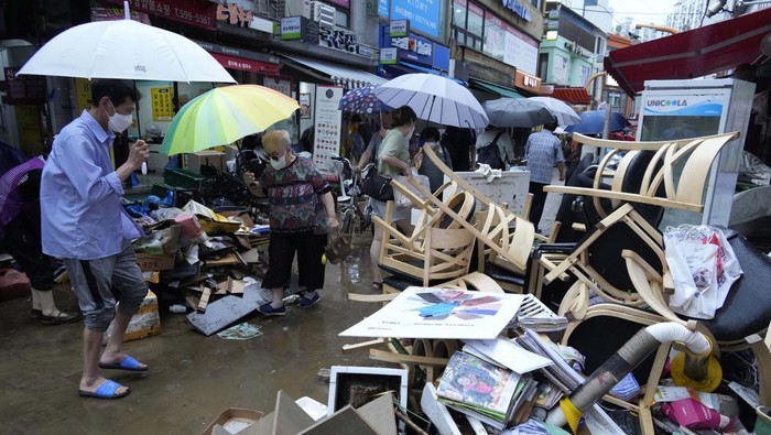 People walk on a damaged road near a subway station in Seoul, South Korea, Tuesday, Aug. 9, 2022. Some of the heaviest rain in decades swamped South Korea's capital region, turning Seoul's streets into car-clogged rivers and sending floods cascading into subway stations.(Kim Ju-sung/Yonhap via AP)