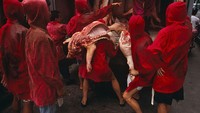 Para buruh pengangkut daging babi kompak memakai atasan merah sambil menunggu daging dioper dari dalam mobil. Foto: VCG via Getty Images/VCG