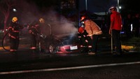 Petugas pemadam kebakaran berusaha memadamkan api yang membakar mobil.