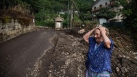 Warga melintas di depan lumpur yang terbawa banjir besar di Monteforte Irpino, Italia.