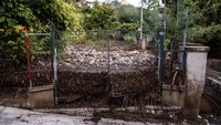 Lumpur dan puing-puing menumpuk di balik pagar akibat banjir yang parah.
