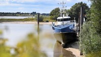 Perahu oleng karena kekurangan debit air. Volume air yang menyusut drastis membuat kapal bersandar di dasar sungai yang mengering di pelabuhan Sungai Rhine di Lobith.