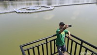 Pengunjung berswafoto berlatar Situ Rawa Kalong. Saat ini, jembatan atau catwalk apung di situ tersebut ditutup dan tidak dapat dilintasi.