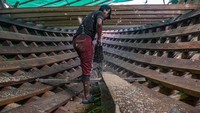 Seorang pengrajin memotong kayu dalam proses produksi perahu nelayan tradisional di Kendari, Sulawesi Tenggara, Minggu (7/8/2022).  