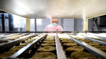 Salah satu pegawai memeriksa mie instan yang sudah jadi dan siap diproses ke tahap selanjutnya. Kembali ke sejarah mie instan, produk mie instan dalam cup juga pertama kali diperkenalkan Nissin pada 1971 dengan nama Cup Noodles. Foto: Getty Images