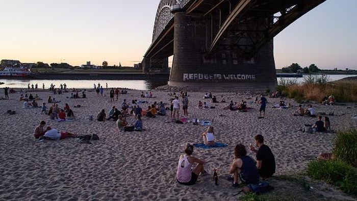 Sungai yang Mengering di Belanda Kini Jadi Tempat Nongkrong NIJMEGEN, NETHERLANDS - AUGUST 10: People enjoy the evening on the banks of the Waal river on August 10, 2022 in Nijmegen, Netherlands. The ongoing drought and the recurring heat waves have cut operation capacities by half along the lower Rhine from Rotterdam to Germany, an important coal transport route destined to steelmakers and power producers. (Photo by Pierre Crom/Getty Images)