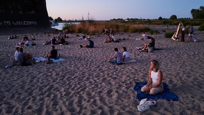 Sungai yang Mengering di Belanda Kini Jadi Tempat Nongkrong NIJMEGEN, NETHERLANDS - AUGUST 10: People enjoy the evening on the banks of the Waal river on August 10, 2022 in Nijmegen, Netherlands. The ongoing drought and the recurring heat waves have cut operation capacities by half along the lower Rhine from Rotterdam to Germany, an important coal transport route destined to steelmakers and power producers. (Photo by Pierre Crom/Getty Images)