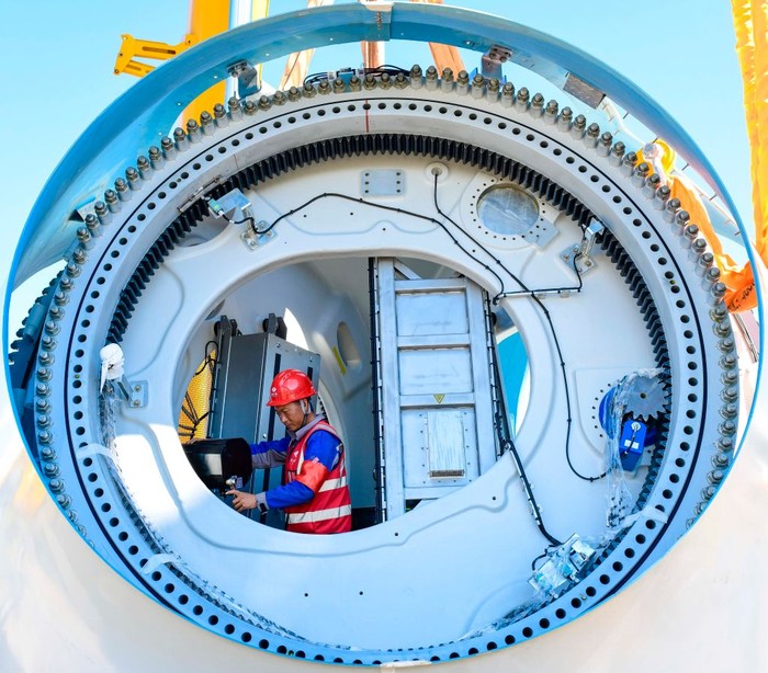 1242431926 XING'AN LEAGUE, CHINA - AUGUST 11, 2022 - Construction personnel work at the construction site of a 200,000-kilowatt wind power project in Hinggan League, Inner Mongolia, China, Aug 11, 2022. The project generates 590 million kilowatt-hours of electricity annually and cuts 550,000 tons of carbon dioxide annually. The project uses a unit with a single capacity of 6.25 MW and a blade length of 182 meters to generate electricity, which is the largest single capacity and longest blade wind turbine in the world. (Photo credit should read CFOTO/Future Publishing via Getty Images)