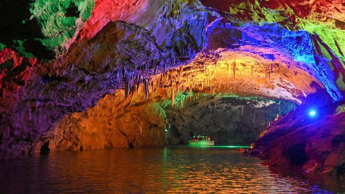 1414166829 BENXI, CHINA - AUGUST 10: Colored lights illuminate the geological formations at the Benxi Water Cave, a large-scale underground karst, on August 10, 2022 in Benxi, Liaoning Province of China. Developed about 500,000 years ago, the cave has more than 400,000 cubic meters internal space and a total length of 5,800 meters. Comprising a dry cave and a water cave, it is the world's longest underground karst cave with water. (Photo by Yu Haiyang/China News Service via Getty Images)