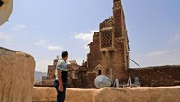 Warga berdiri di depan reruntuhan bangunan kuno. Kota Tua Sanaa merupakan salah satu situs Warisan Dunia UNESCO. Daerah tersebut diyakini telah dihuni selama lebih dari dua milenium.