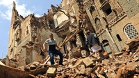 Warga melintasi bangunan rusak akibat diguyur hujan lebat.  Bangunan tua itu mempunyai arsitekturnya yang unik, fondasi, dan lantai dari bata merah. Beberapa gedung tinggi di Sanaa diyakini sebagai gedung tinggi pertama di dunia.