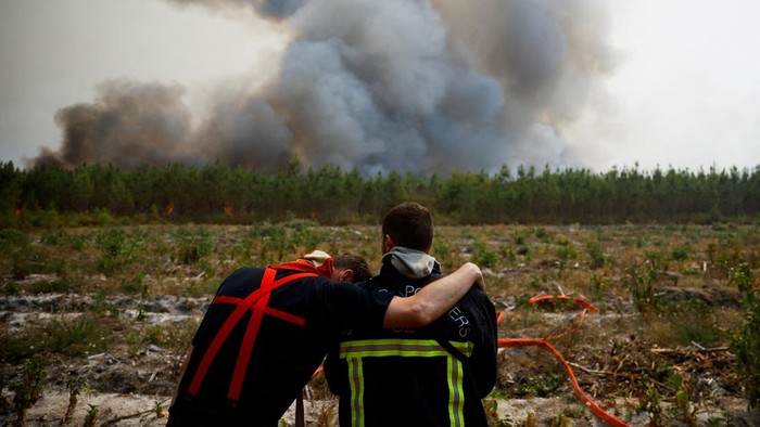 Firefighters embrace as they work to contain a fire in Saint-Magne, as wildfires continue to spread in the Gironde region of southwestern France, August 11, 2022. REUTERS/Stephane Mahe     TPX IMAGES OF THE DAY