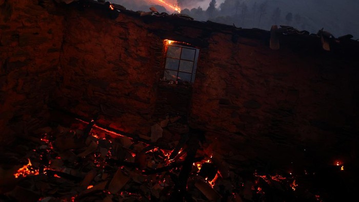 A person rides a motorcycle on a burned area during a wildfire in Videmonte, Celorico da Beira, Portugal, August 11, 2022. REUTERS/Pedro Nunes