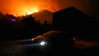 Sebuah mobil melaju kencang ketika melewati wilayah kebakaran hutan di Videmonte. Terlihat langit berwarna oranye akibat api yang mulai menjalar ke sekitar hutan.