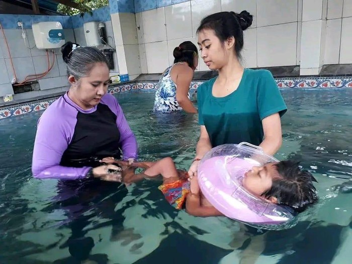 Ketua Yayasan De Legong Anak Bangsa, Putu Deasy Krisna Dewi Asmady (baju hitam ungu) saat melakukan terapi pada anak penderita Cerebral Palsy.
