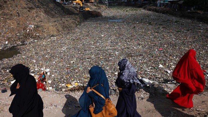 A boy walks over a land of waste in Dhaka, Bangladesh, August 11, 2022. REUTERS/Mohammad Ponir Hossain