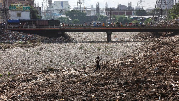 Penampakan Kanal di Bangladesh yang Jadi Dataran Gegara Sampah A boy walks over a land of waste in Dhaka, Bangladesh, August 11, 2022. REUTERS/Mohammad Ponir Hossain
