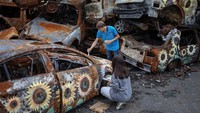 Seniman Ukraina, Viacheslav Rybka dan Olena Yanko, melukis di mobil-mobil yang hancur akibat serangan Rusia di Ukraina.  