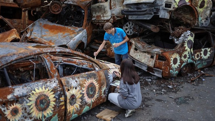 A Ukrainian artist Viacheslav Rybka paints a car destroyed during Russia's attack on Ukraine and then collected from different places in the town of Irpin in Kyiv region, Ukraine August 10, 2022. REUTERS/Gleb Garanich     TPX IMAGES OF THE DAY