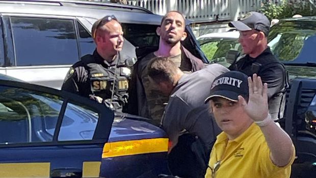 ADDS NAME OF DETAINED PERSON Law enforcement officers detain Hadi Matar, 24, of Fairview, N.J., outside the Chautauqua Institution, Friday, Aug. 12, 2022, in Chautauqua, N.Y.. Salman Rushdie, the author whose writing led to death threats from Iran in the 1980s, was attacked and apparently stabbed in the neck Friday by Matar who rushed the stage as he was about to give a lecture at the institute in western New York. (Charles Fox via AP)