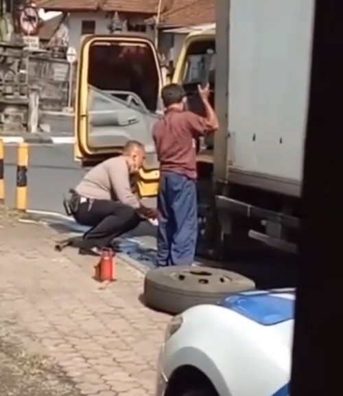Polisi bantu sopir truk mengganti ban di perempatan Jalan Raya Lukluk, Kecamatan Mengwi, Kabupaten Badung.