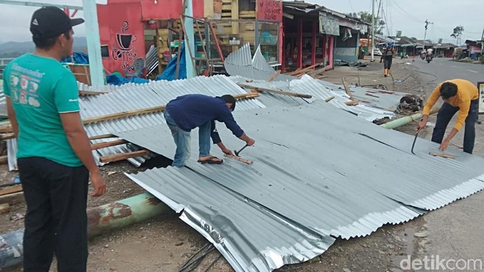 Warga memperbaiki warung mereka yang rusak.