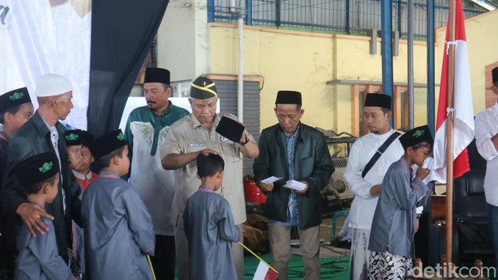 Anak-anak mencium bendera setelah menerima santunan dari pensiunan tentara sekaligus pengusaha asal Kudus, Haryanto, Minggu (14/8/2022).
