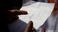 Seorang pembeli mengeluarkan catatan barang yang akan dibeli di Pasar Mester. Banyak warga yang belanja dalam jumlah besar atau banyak.