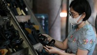 Seorang pekerja tengah memeriksa sandal karet yang dijual di tokonya. Tertarik membelinya juga detikers?