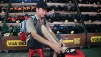 Seorang pelanggan tengah mencoba sandal karet di sebuah toko di Hanoi. Vua Dep Lop, yang dimulai sebagai usaha kecil dan menjadi pemimpin sandal karet Vietnam, menjual alas kaki tersebut dengan harga sekitar Rp 150 ribu sepasang.