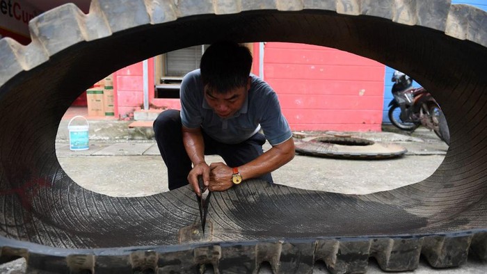 Ini Sandal Unik Vietnam yang Terbuat dari Barang Bekas Perang Dunia This photo taken on July 8, 2022 shows Nguyen Tien Cuong pushing a truck tyre outside a workshop in Hanoi, before it's transformed into rubber tyres. - Made from recycled military truck or aircraft tyres, Vietnam's hand-made rubber sandals, the famously rugged footwear of the Viet Cong, have travelled vast distances over the decades. - TO GO WITH AFP STORY Vietnam-history-lifestyle-sandals by Tran Thi Minh Ha (Photo by Nhac NGUYEN / AFP) / TO GO WITH AFP STORY Vietnam-history-lifestyle-sandals by Tran Thi Minh Ha (Photo by NHAC NGUYEN/AFP via Getty Images)
