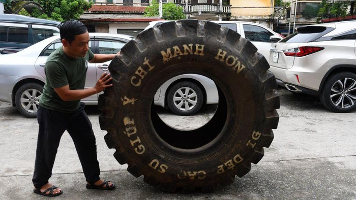 Ini Sandal Unik Vietnam yang Terbuat dari Barang Bekas Perang Dunia This photo taken on July 8, 2022 shows Nguyen Tien Cuong pushing a truck tyre outside a workshop in Hanoi, before it's transformed into rubber tyres. - Made from recycled military truck or aircraft tyres, Vietnam's hand-made rubber sandals, the famously rugged footwear of the Viet Cong, have travelled vast distances over the decades. - TO GO WITH AFP STORY Vietnam-history-lifestyle-sandals by Tran Thi Minh Ha (Photo by Nhac NGUYEN / AFP) / TO GO WITH AFP STORY Vietnam-history-lifestyle-sandals by Tran Thi Minh Ha (Photo by NHAC NGUYEN/AFP via Getty Images)