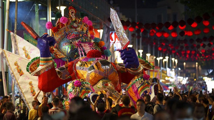Ethnic Chinese throw paper offerings during burning of a giant paper statue of the Chinese deity 