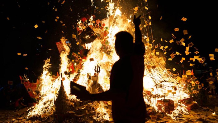 Ethnic Chinese throw paper offerings during burning of a giant paper statue of the Chinese deity 