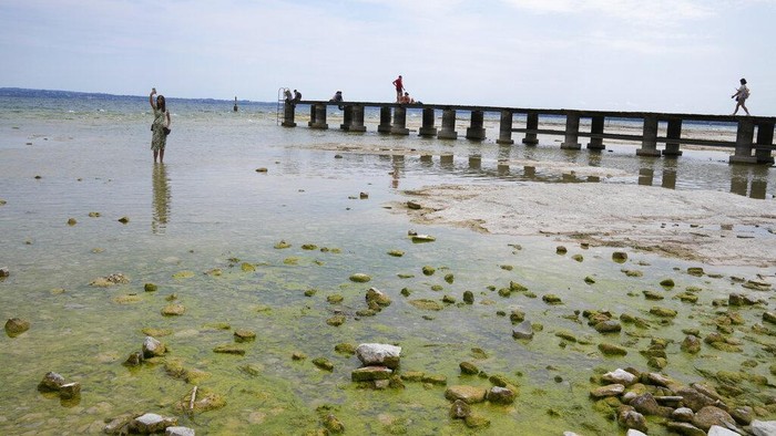 Potret Danau Terbesar di Italia Airnya Menyusut Akibat Kekeringan Parah A view of the peninsula of Sirmione, on Garda lake, Italy, Friday, Aug. 12, 2022. Lake Garda water level has dropped critically following severe drought resulting in rocks to emerge around the Sirmione Peninsula. (AP Photo/Antonio Calanni)
