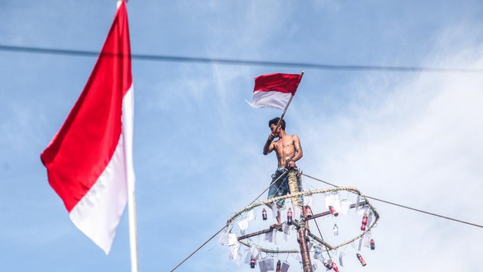 Seorang peserta mengibarkan bendera merah putih saat berhasil memanjat pohon pinang dalam lomba panjat pinang kemerdekaan di Kelurahan Langkai, Palangka Raya, Kalimantan Tengah, Sabtu (13/8/2022). Acara perlombaan tersebut berlangsung dalam rangka memeriahkan dan menyambut HUT ke-77 Kemerdekaan Republik Indonesia. ANTARA FOTO/Makna Zaezar/aww.