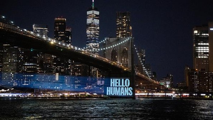 NEW YORK, NEW YORK - AUGUST 14: People gather around to watch as Greenpeace activists illuminate the Brooklyn Bridge with projections of the ocean and messages that read, 