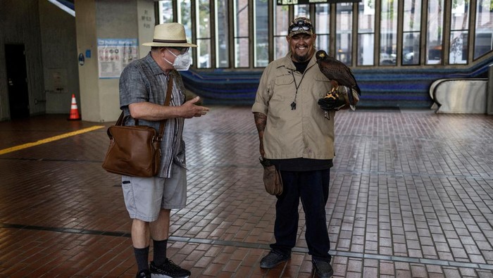 Ricky Ortiz walks around with Pac-Man, a 5-year-old Harris's hawk as they chase pigeons aways from El Cerrito del Norte Metro station in El Cerrito, California, U.S. August 10, 2022. REUTERS/Carlos Barria