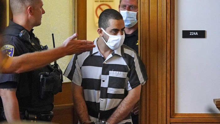 Ini Sosok Hadi Matar, Pelaku Penikaman Salman Rushdie Hadi Matar, 24, center, arrives for an arraignment in the Chautauqua County Courthouse in Mayville, N.Y., Saturday, Aug. 13, 2022. Matar, who is accused of carrying out a stabbing attack against “Satanic Verses” author Salman Rushdie has entered a not-guilty plea in a New York court on charges of attempted murder and assault. An attorney for Matar entered the plea on his behalf during an arraignment hearing. (AP Photo/Gene J. Puskar)