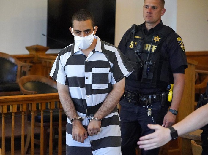 Hadi Matar, 24, center, arrives for an arraignment in the Chautauqua County Courthouse in Mayville, N.Y., Saturday, Aug. 13, 2022. Matar, who is accused of carrying out a stabbing attack against “Satanic Verses” author Salman Rushdie has entered a not-guilty plea in a New York court on charges of attempted murder and assault. An attorney for Matar entered the plea on his behalf during an arraignment hearing.  (AP Photo/Gene J. Puskar)