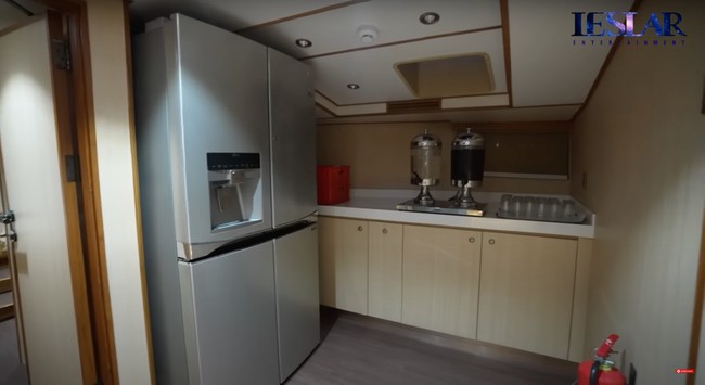 Bagian dapur di dalam kapal juga cukup luas dan terdiri dari 2 sisi di bagian kiri dan kanan. Salah satu sisinya dilengkapi dengan sebuah kulkas 2 pintu yang cukup besar, lemari penyimpanan, juice dispenser, dan beberapa gelas yang sudah tersusun rapih. Foto: YouTube/Leslar Entertainment