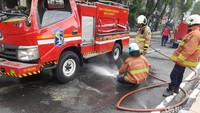 Petugas membersihkan jalan setelah mobil PMK yang terguling bisa berdiri kembali/Foto: Esti Widiyana/detikJatim