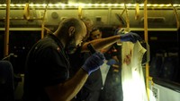Seorang petugas Israel memeriksa kain bernoda darah di dalam bus. Menurut petugas setempat, pria bersenjata yang menjadi pelaku penyerangan telah menyerahkan diri kepada otoritas Israel.