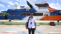 Mantri BRI, Fremar Refel berpose di depan kapal khusus pelayanan Bnk BRI. Setiap 6 hari dalam seminggu, Fremar harus menyusuri besarnya ombak lautan Anambas bersama Teras BRI Kapal atau Bank Terapung.   