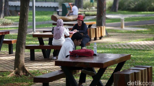 Selain berolahraga, ada sebagian warga yang memilih bersantai dengan duduk dan berbincang di taman.