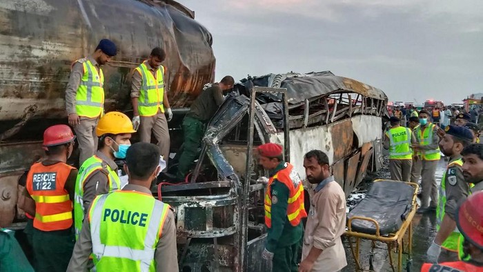 Rescue workers search for victims in the burnt wreckage of a bus following an overnight collision between a passenger bus and an oil tanker in Multan district on August 16, 2022. - At least 20 people were killed when a bus caught fire after colliding with an oil tanker in Pakistan on August 16, police said. (Photo by AFP)