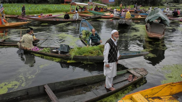 SRINAGAR, KASHMIR, INDIA - 2022/08/02: A Kashmiri man rows a boat ferrying fresh flowers in the depth of Dal lake. Dal Lake is famed for its floating vegetable market which supplies varieties of vegetables all year to many towns across the Kashmir valley. This floating vegetable market comprises of many floating gardens as well as local varieties of organic vegetables. It is one of the very famous floating markets in the world. The vegetable market opens at 4o clock in the morning even before the sun rises and closes within the next two hours. (Photo by Saqib Majeed/SOPA Images/LightRocket via Getty Images)