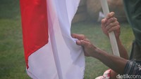 Para pejuang memegang bendera merah putih yang tidak boleh diturunkan oleh penjajah. 