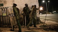 Polisi bersembunyi dibalik bangunan kumuh serta menembakkan gas air mata dan menembakkan senapan ke demonstran di Kisumu, Kenya. (Ed Ram/Getty Images)